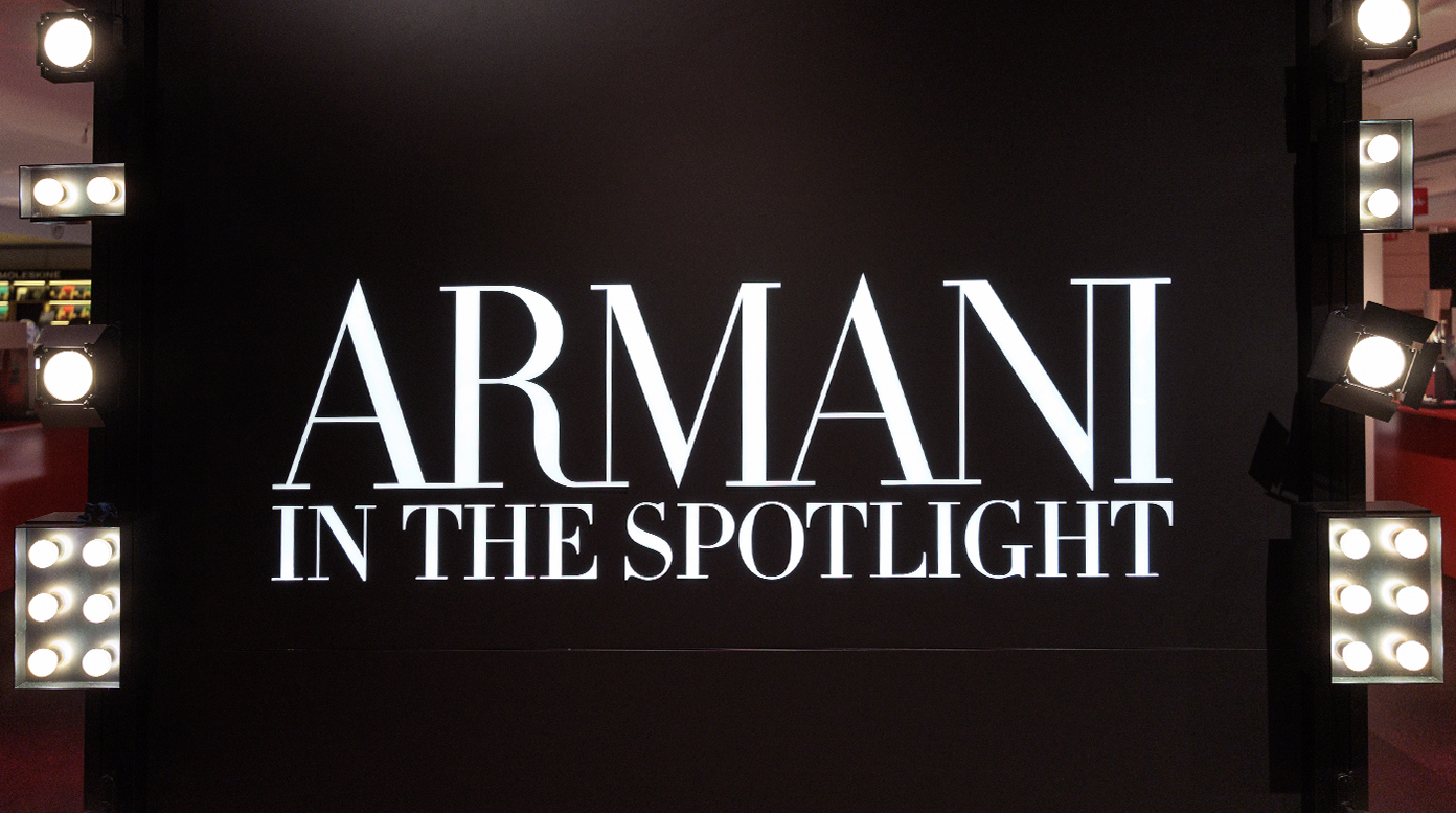 Armani Beauty takeover at Rinascente Milano during Fashion Week, with illuminated arches and branded red window displays.