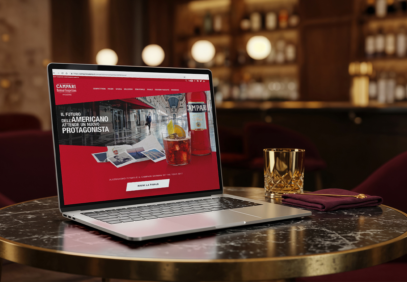 Campari Barman Competition website homepage displayed on a laptop in a bar setting.